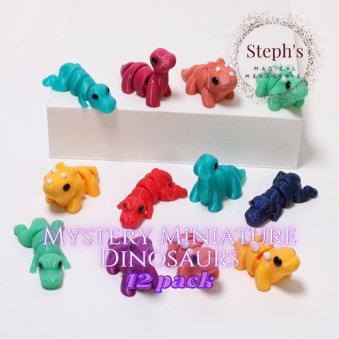 A collection of small, colorful dinosaur figurines arranged on and around a white block. The set includes twelve miniature dinosaurs in vibrant colors like blue, red, orange, green, purple, and yellow. The text 'Steph's Magical Menagerie' is displayed in the top right corner, and 'Mystery Miniature Dinosaurs 12 pack' is written at the bottom center."