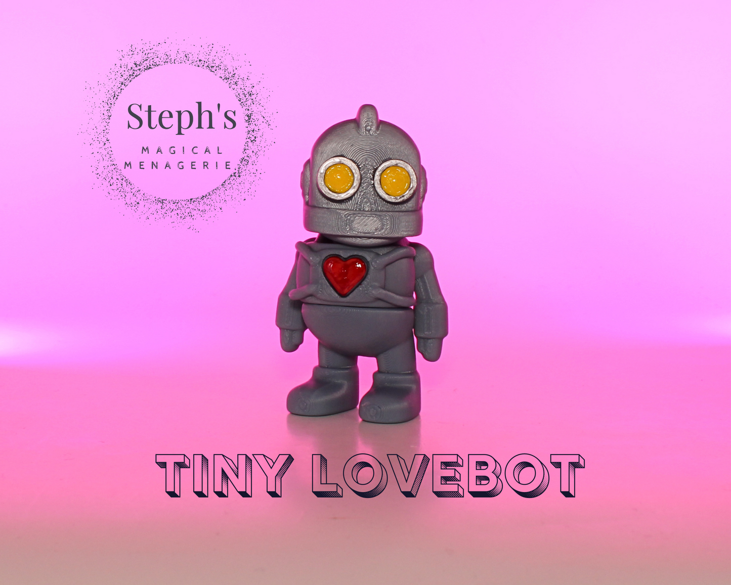 Toy robot with a red heart on a pink gradient background, branded 'Steph's Magical Menagerie'.